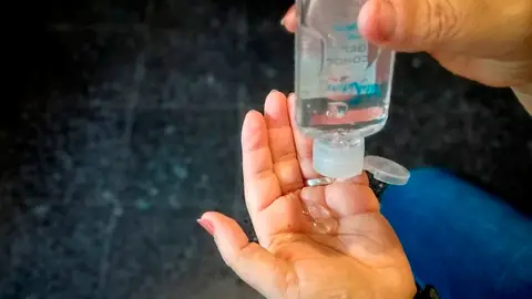 Imagen de una mujer echándose en las manos un gel hidroalcóholico Imagen de una mujer echándose en las manos un gel hidroalcóholico