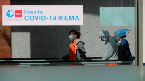 Trabajadores sanitarios caminan por una cinta desplazadora en el hospital temporal de Ifema coronavirus