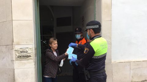 Un agente de la Polic&iacute;a Local de Crevillent entrega una mascarilla a una vecina de la localidad.