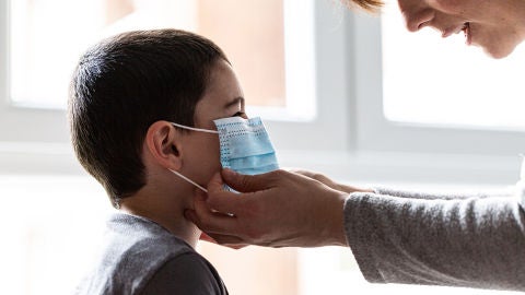 Una mujer coloca una mascarilla a un ni&ntilde;o