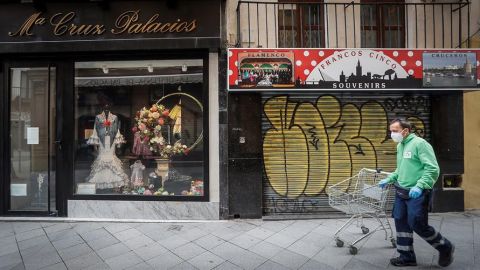 Un hombre con mascarilla frente a dos comercios cerrados por el coronavirus