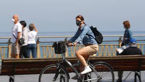 Una mujer pasea en bicicleta protegida con una mascarilla Una mujer pasea en bicicleta protegida con una mascarilla