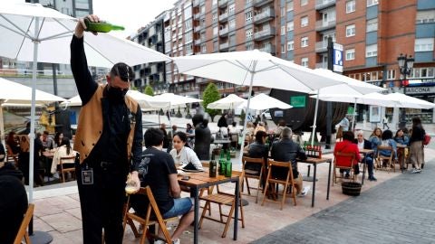 Un camarero escancia sidra en una terraza de Asturias
