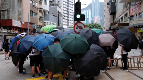 Manifestantes se protegen del lanzamiento de gases lacrim&oacute;genos de la Polic&iacute;a en Hong Kong