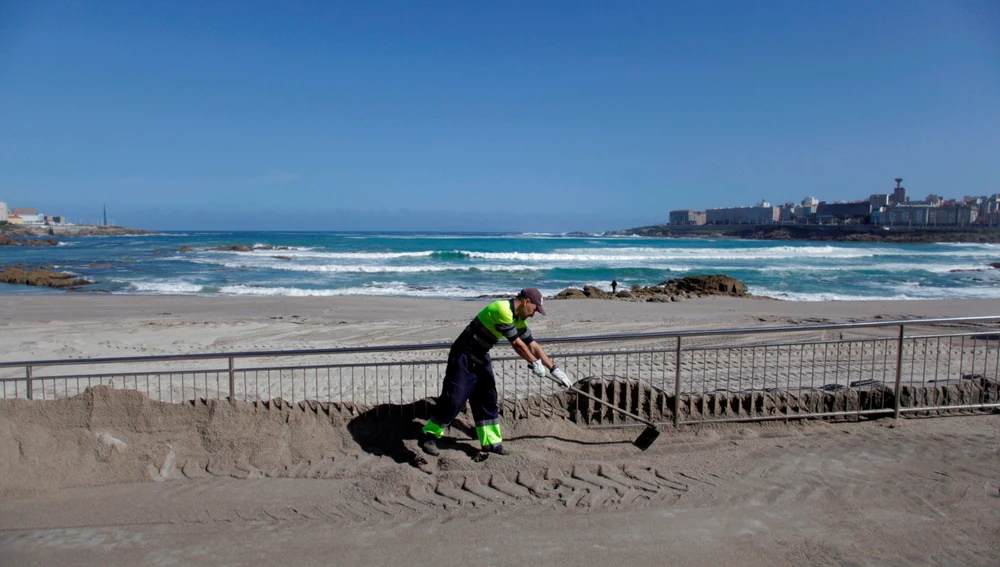 Un operario del concello de A Coruña trabaja en el acondicionando la playa de Riazor