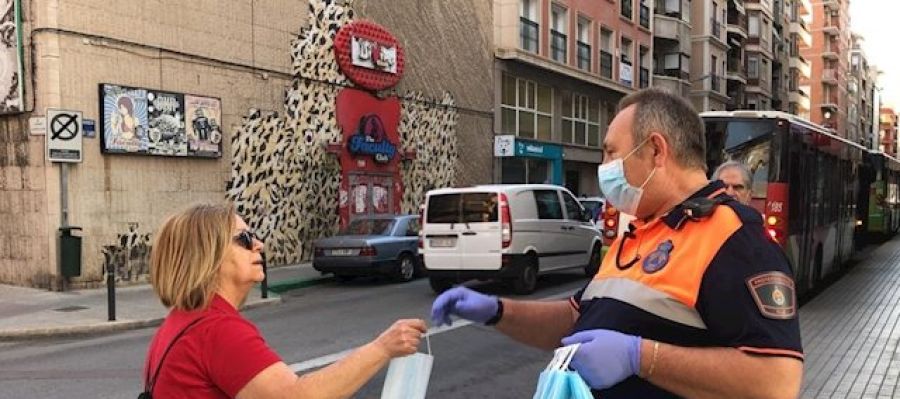 Un voluntario de Protección Civil entrega una mascarilla a una mujer en Elche. Un voluntario de Protección Civil entrega una mascarilla a una mujer en Elche.