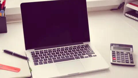 Imagen de archivo de una mesa de escritorio con un ordenador y una calculadora Imagen de archivo de una mesa de escritorio con un ordenador y una calculadora