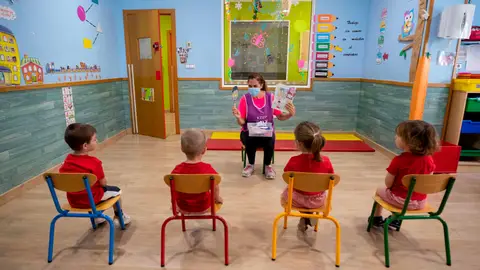 Una educadora de un centro de educación infantil les cuenta un cuento a varios niños y niñas en Murcia niños