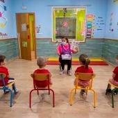 Una educadora de un centro de educación infantil les cuenta un cuento a varios niños y niñas en Murcia 