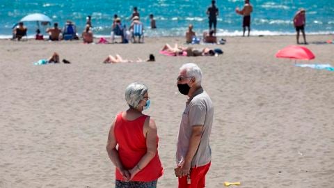 Personas con mascarilla en una playa (Archivo)