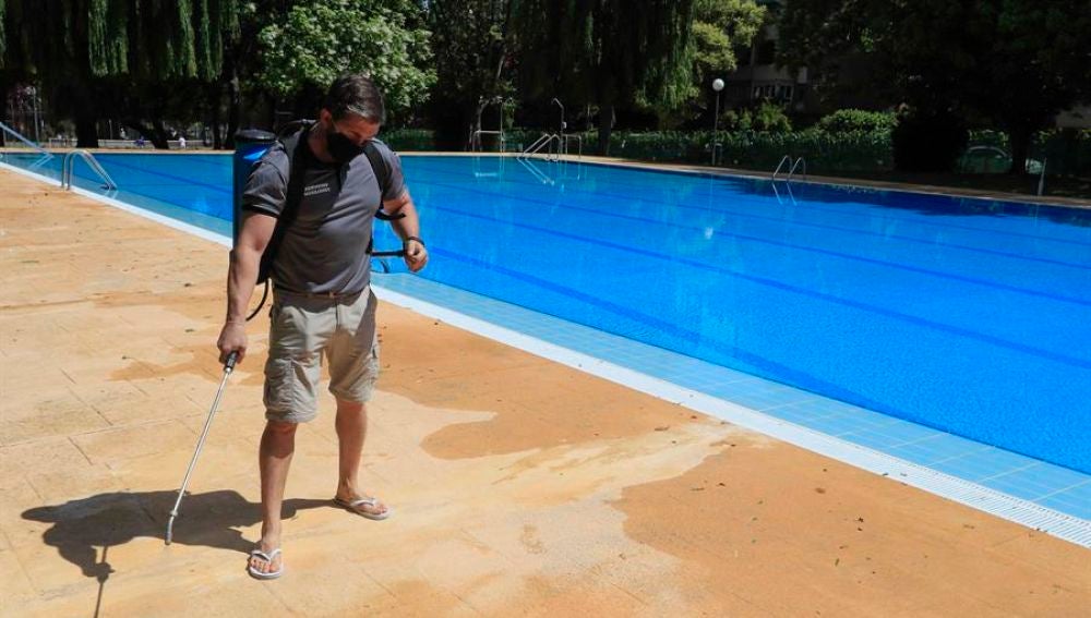 Un operario desinfecta el perímetro de una piscina.