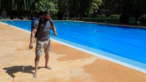 Un operario desinfecta el per&iacute;metro de una piscina.