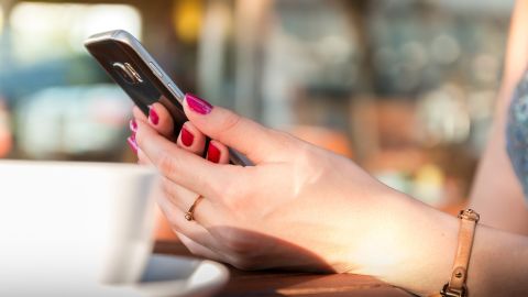 Imagen de una mujer usando un tel&eacute;fono m&oacute;vil en un bar