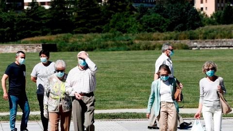 Un grupo de personas con mascarilla pasean por un parque