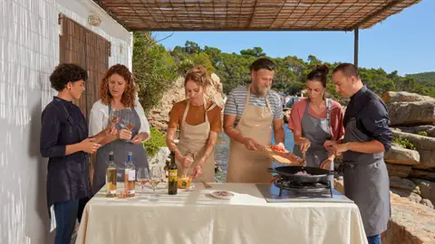Pla general d'un grup de persones fent un tast de vins i cuinant un plat durant una excursió enogastronòmica pels camins de ronda de la Costa Brava Pla general d'un grup de persones fent un tast de vins i cuinant un plat durant una excursió enogastronòmica pels camins de ronda de la Costa Brava