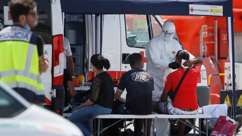 Los sanitarios de la Cruz Roja, enfundados en EPI 's, atienden a varios de los 29 inmigrantes que han sido interceptados tras alcanzar tierra a la altura de la ciudad de Alicante, la localidad de Guardamar del Segura y la costa de Orihuela a bordo de sendas embarcaciones de tipo patera
