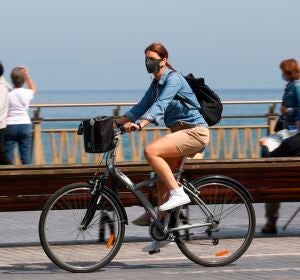 Una mujer pasea en bicicleta protegida con una mascarilla por el paseo de la Zurriola de San Sebastián Una mujer pasea en bicicleta protegida con una mascarilla por el paseo de la Zurriola de San Sebastián