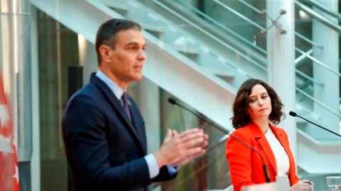 Isabel D&iacute;az Ayuso mira a Pedro S&aacute;nchez durante su comparecencia conjunta en la Puerta del Sol