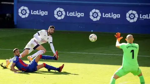 El delantero del Osasuna Enric Gallego (c) remata ante el jugador de la SD Eibar Burgos, y el guardameta Dimitrovic