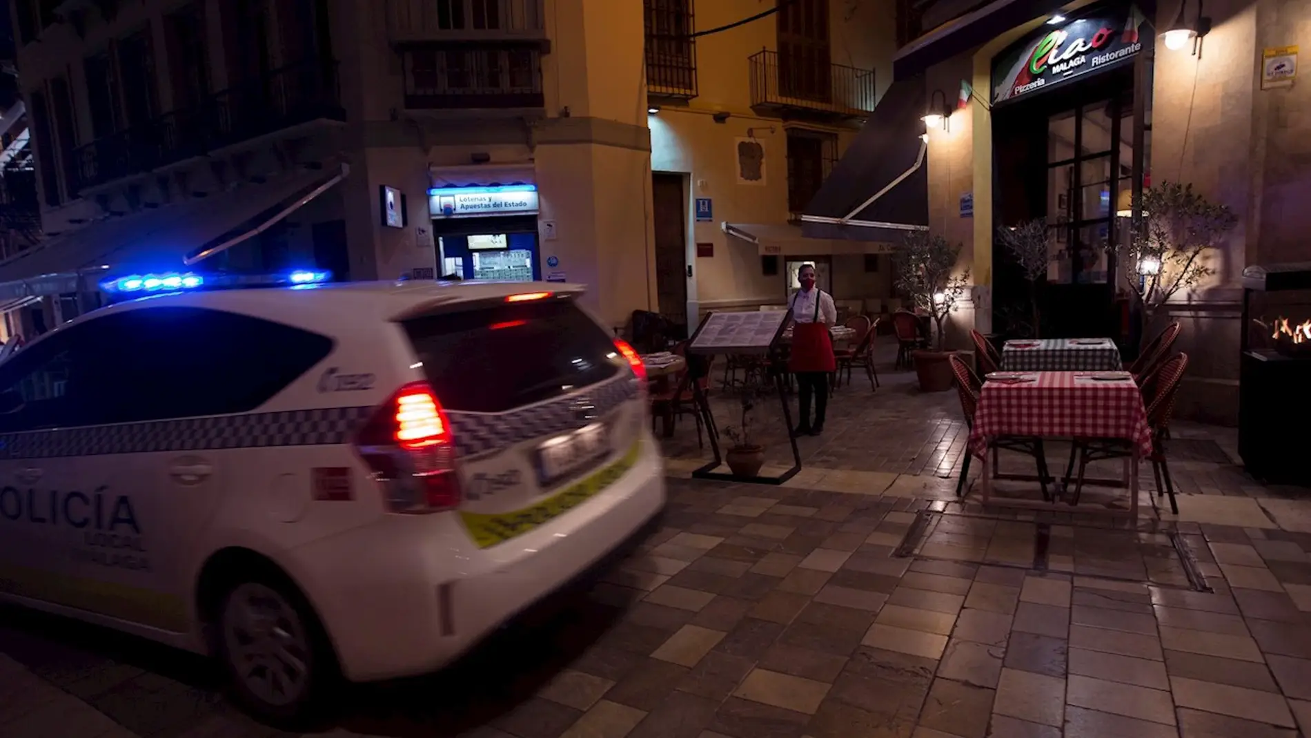 Un coche de la policía Local pasa por la puerta de un restaurante en Málaga