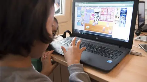 Una niña manejando un ordenador Una niña manejando un ordenador