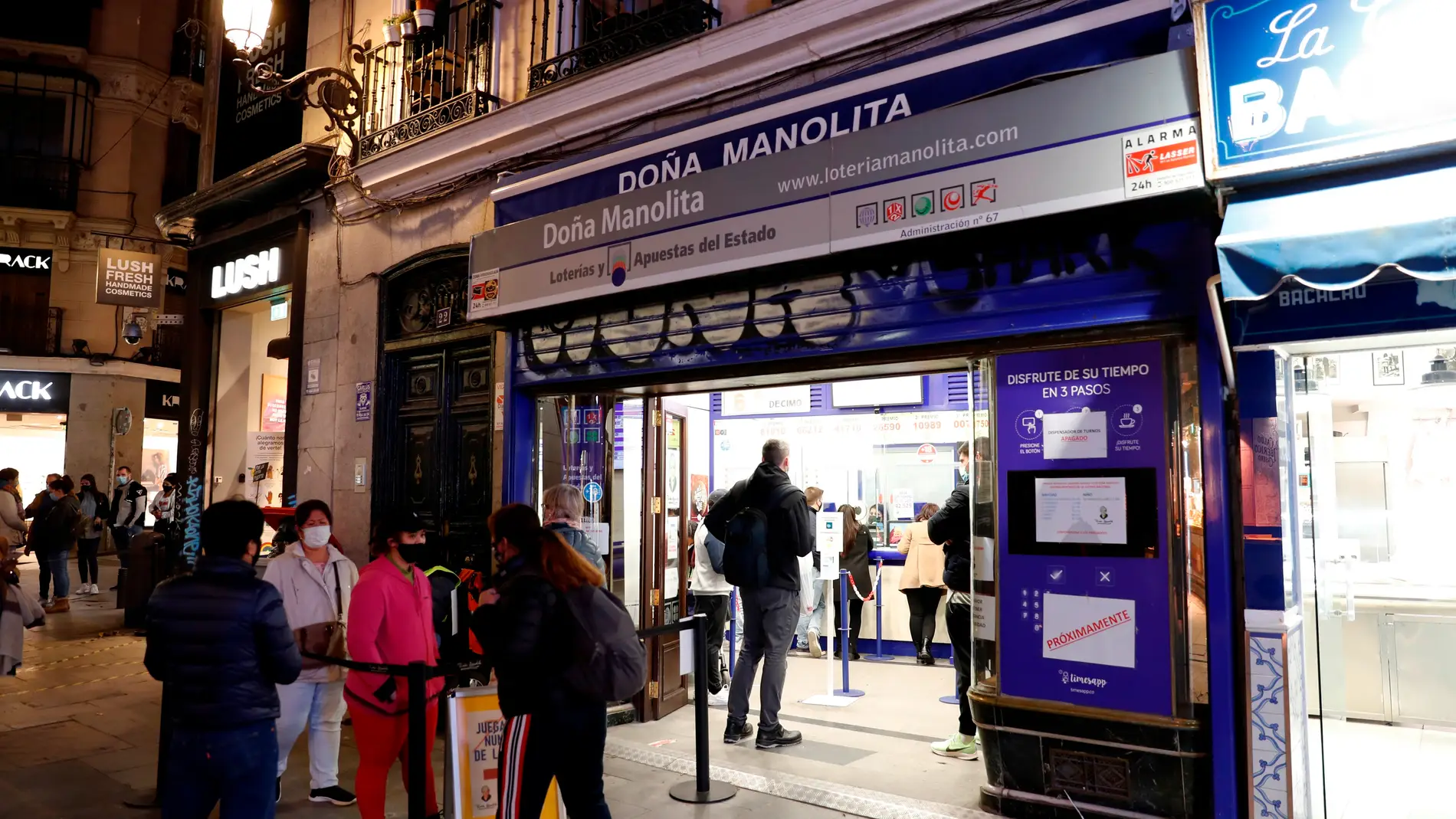 Varias personas esperan a las puertas de la administración de Lotería de Doña Manolita, en Madrid.