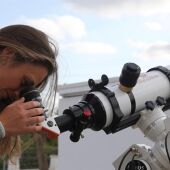 Una chica observa a través de un telescopio.