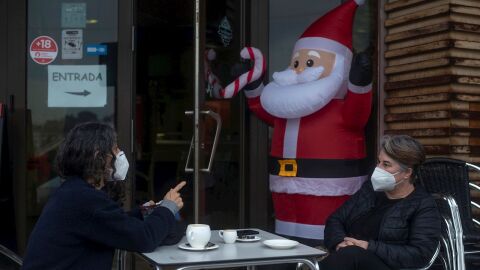 Dos personas toman algo con mascarilla en una terraza en Nochebuena