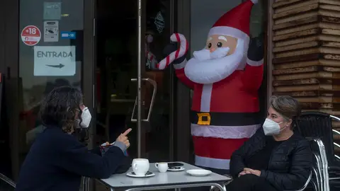 Dos personas toman algo con mascarilla en una terraza en Nochebuena Dos personas toman algo con mascarilla en una terraza en Nochebuena
