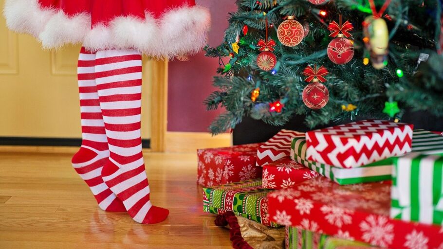 Una ni&ntilde;a coloca el &aacute;rbol de Navidad lleno de regalos