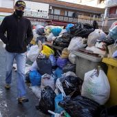 Una persona pasea junto a las bolsas de basura acumuladas en Madrid.