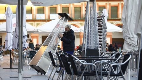 Un trabajador recoge el mobiliario de la terraza de un restaurante en el centro de C&oacute;rdoba