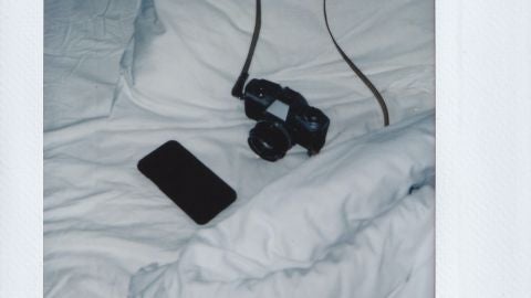 Una c&aacute;mara de fotos y un m&oacute;vil en una cama