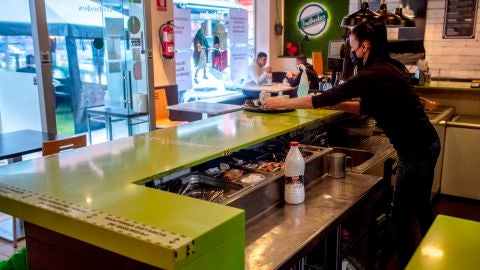 Mujer detr&aacute;s de la barra con mascarilla por el coronavirus