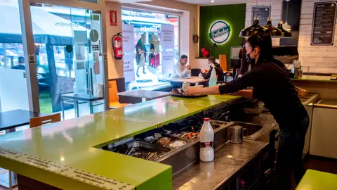 Mujer detrás de la barra con mascarilla por el coronavirus Mujer detrás de la barra con mascarilla por el coronavirus