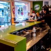 Mujer detrás de la barra con mascarilla por el coronavirus