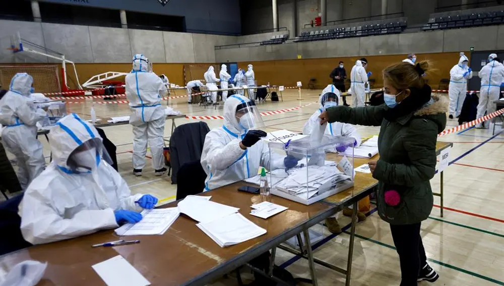  Varias personas equipadas con equipos de protección individual (EPI), trabajan en las mesas electorales del Polideportivo Municipal de la España Industrial de Barcelona