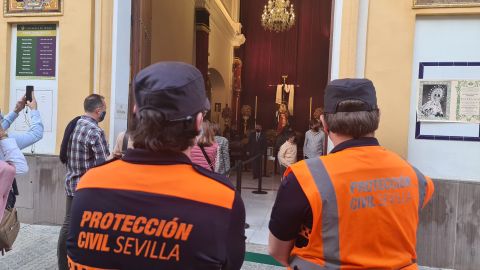 Agentes de protección civil controlan que se cumplan las medidas ante las puertas de una iglesia de Sevilla