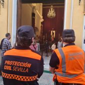 Agentes de protección civil controlan que se cumplan las medidas ante las puertas de una iglesia de Sevilla