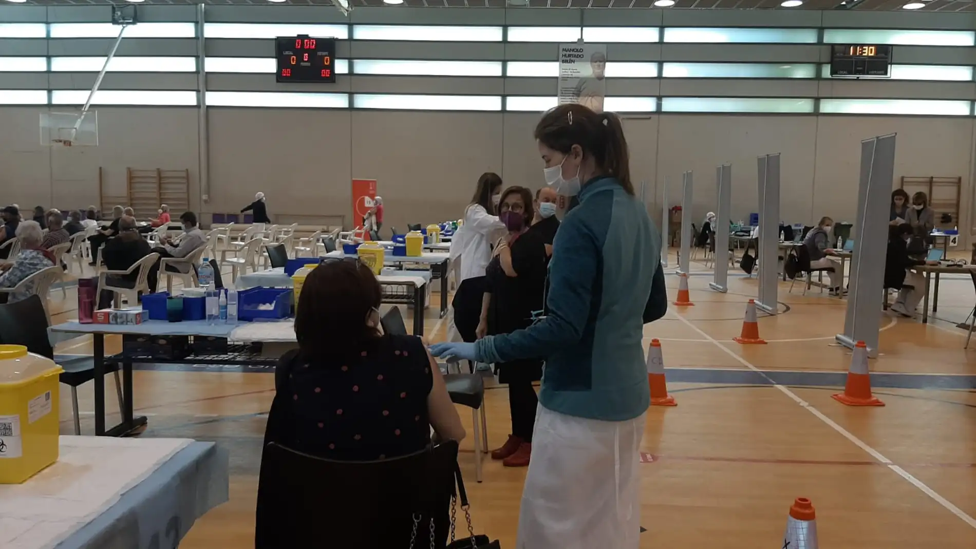 Una sanitaria vacuna a una ciudadana en el pabellón deportivo El Toscar de Elche.