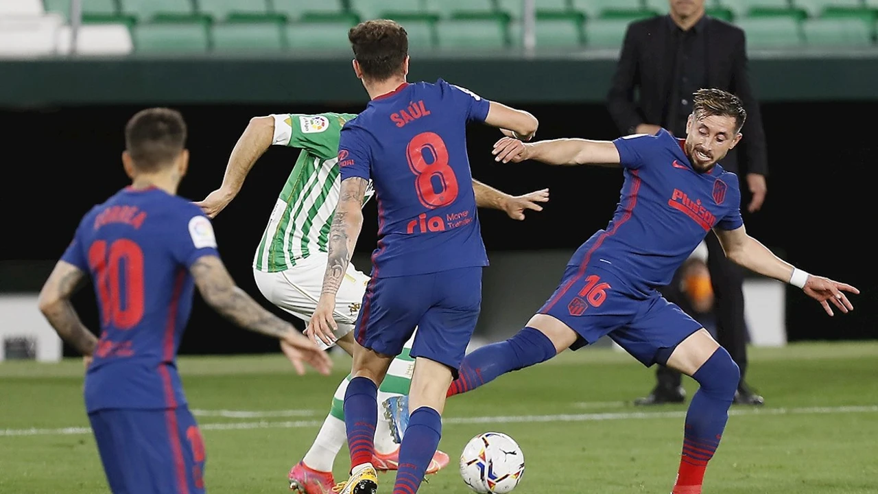 Los jugadores del Atlético de Madrid, Saúl Ñiguez y el mexicano Hector Herrera, disputan el balón ante el jugador del Betis