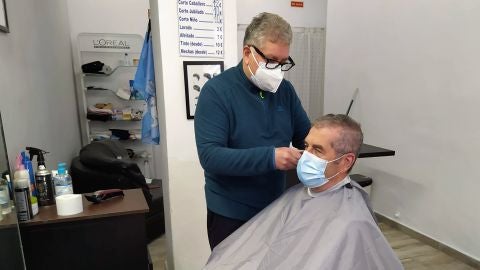 Mario Andrés atiende a un cliente habitual, José Rodríguez, en su peluquería de la calle Capità Vilà de Palma