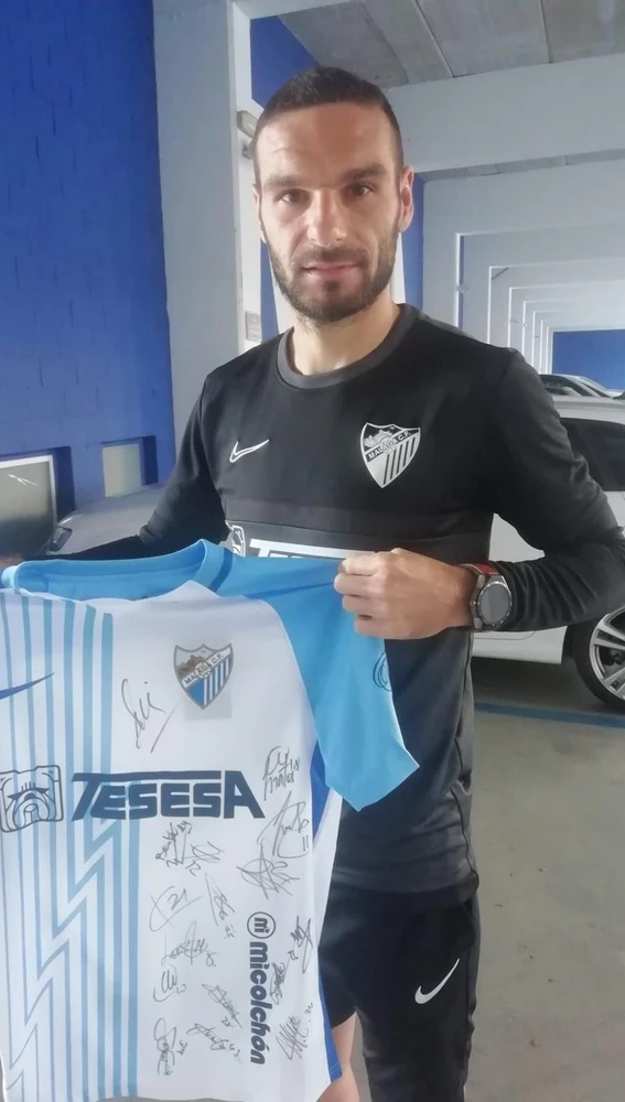 David Lombán muestra una camiseta del Málaga CF firmada por la plantilla