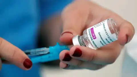 mujer sosteniendo una vacuna de AstraZeneca mujer sosteniendo una vacuna de AstraZeneca