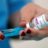 mujer sosteniendo una vacuna de AstraZeneca mujer sosteniendo una vacuna de AstraZeneca