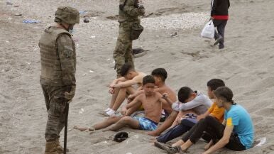 Miembros del Ejército de Tierra vigilan a un grupo de inmigrantes menores tras su entrada en Ceuta