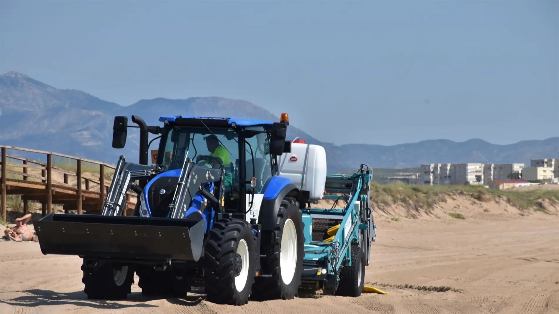 Tractor limpiando una de las playas de Elche.