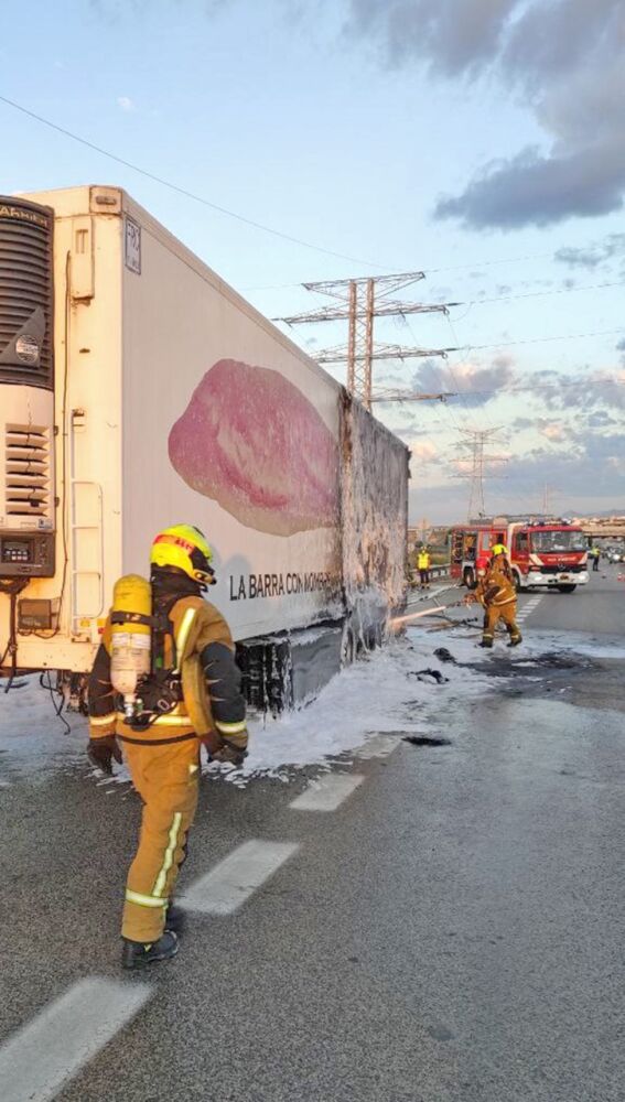 Bomberos junto al camión incendiado.