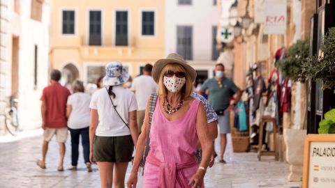 Una mujer caminando con mascarilla por la calle