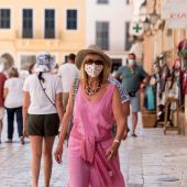 Una mujer caminando con mascarilla por la calle